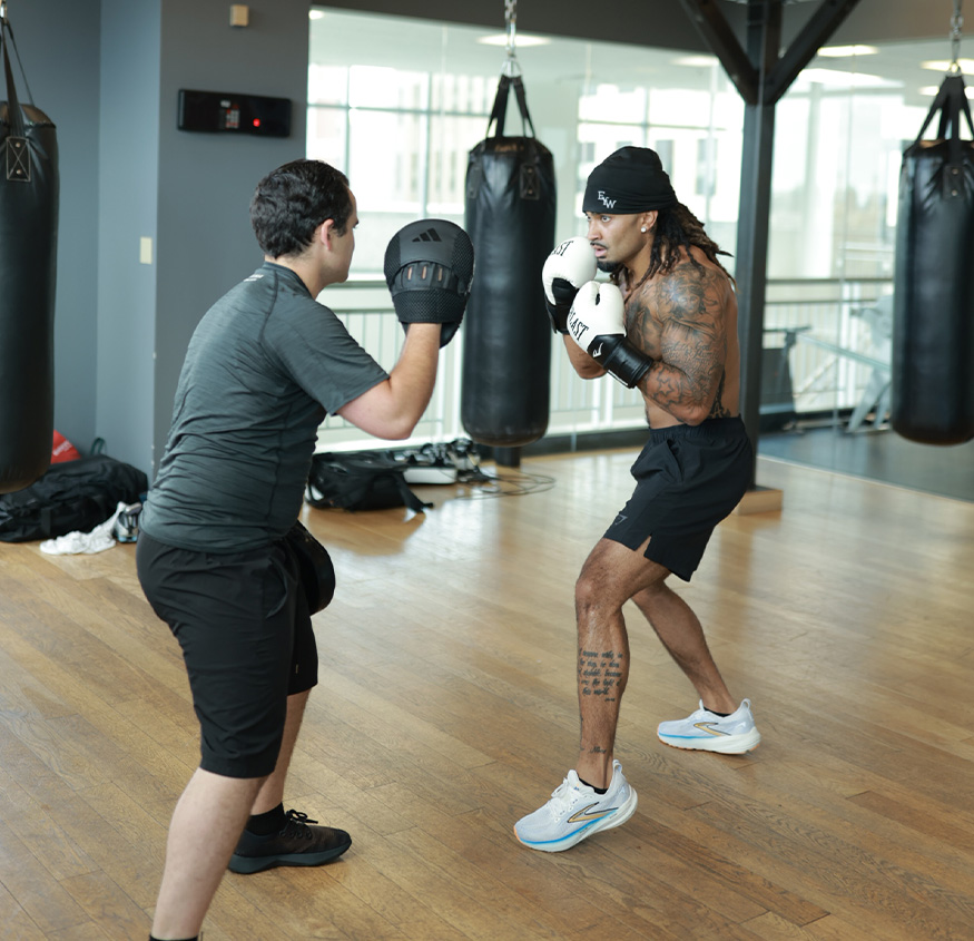Coach is boxing with another person.