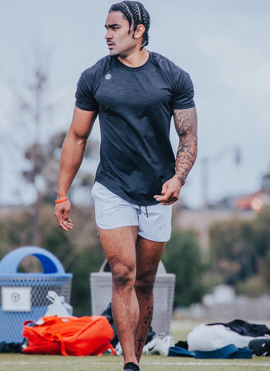 Coach is walking outside in exercise clothing.